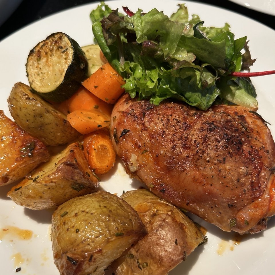 Gebratenes Hähnchen mit Rosmarinkartoffeln, Ofengemüse und Salat auf einem Teller