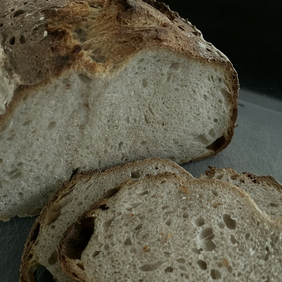 Angeschnittenes Weizen-Roggen-Sauerteigbrot mit kräftiger Kruste und sichtbar lockerer Krume