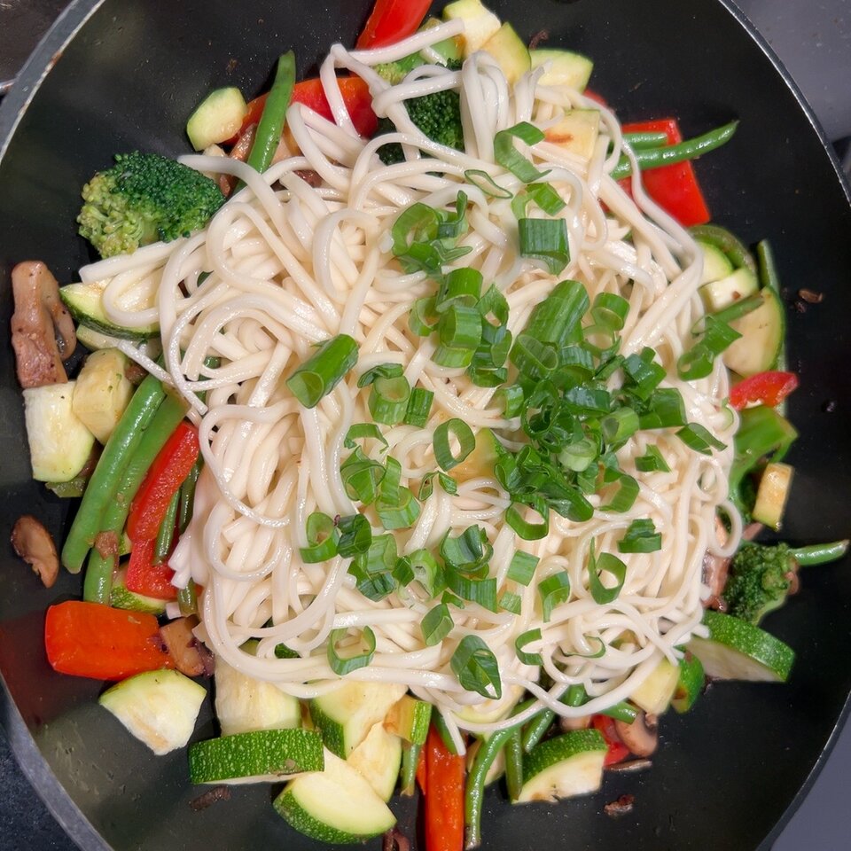 Udon-Nudeln mit Brokkoli, Bohnen, Paprika, Zucchini und Frühlingszwiebeln im Wok