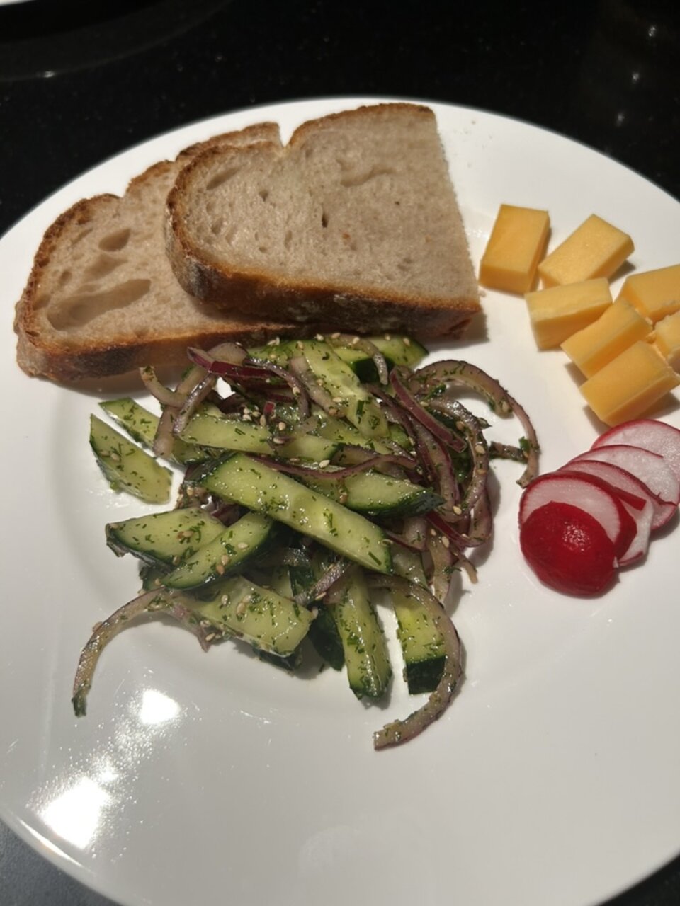 Gurkensalat mit Dill, roter Zwiebel und Sesam zu Brot, Käse und Radieschen