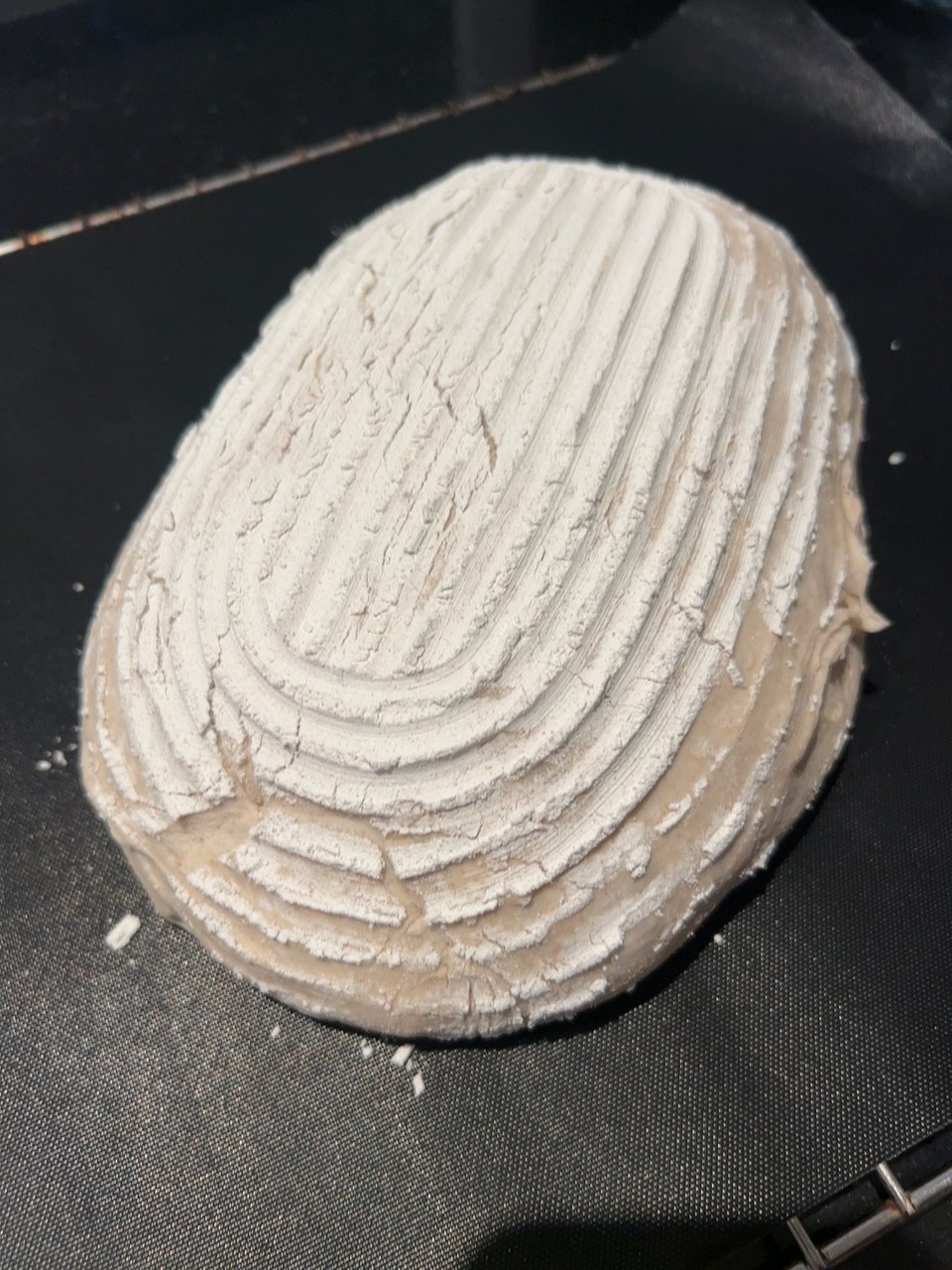 Bemehlter Brotteigling mit Gärkörbchenmuster und länglichem Einschnitt vor dem Backen