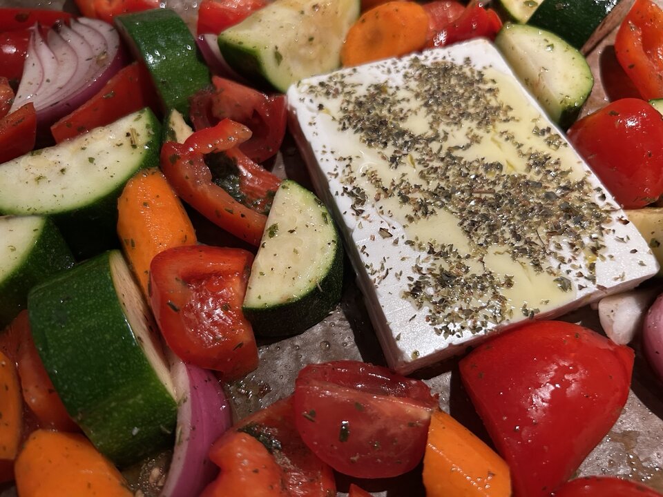 Fetablock mit Kräutern, Olivenöl, Zucchini, Paprika, Tomaten und roter Zwiebel