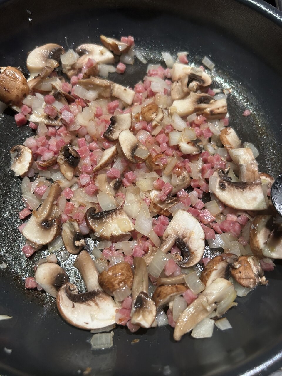 Kräftig angebratene Speckwürfel, Zwiebeln und Champignons in einer Pfanne