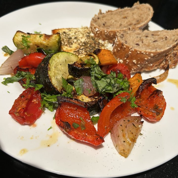 Mediterranes Ofengemüse mit gebackenem Feta und Brot auf einem Teller